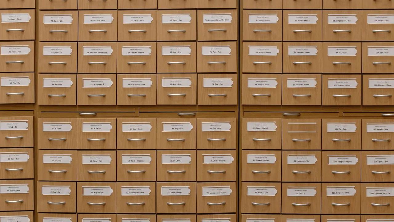 Mur de petits tiroirs d'archives en bois, chacun muni de son étiquette