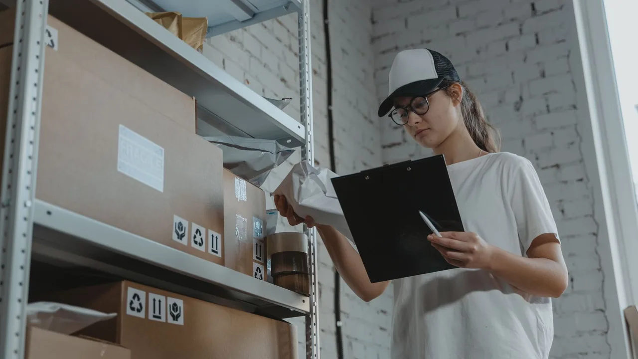 Employée d'entrepôt avec un porte-bloc vérifiant des cartons sur une étagère