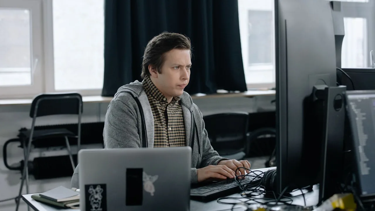 Un programmeur concentré devant deux écrans dans un bureau