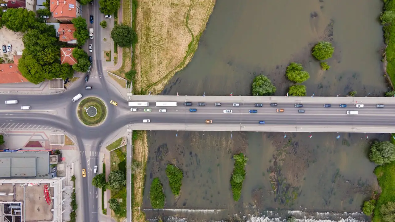 Vue aérienne d'un pont routier et d'un rond-point au bord d'une rivière, avec des voitures en circulation