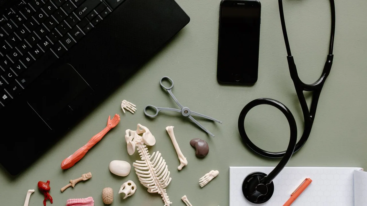 Vue de dessus d'un bureau avec ordinateur portable, smartphone, stéthoscope et figurines d'os