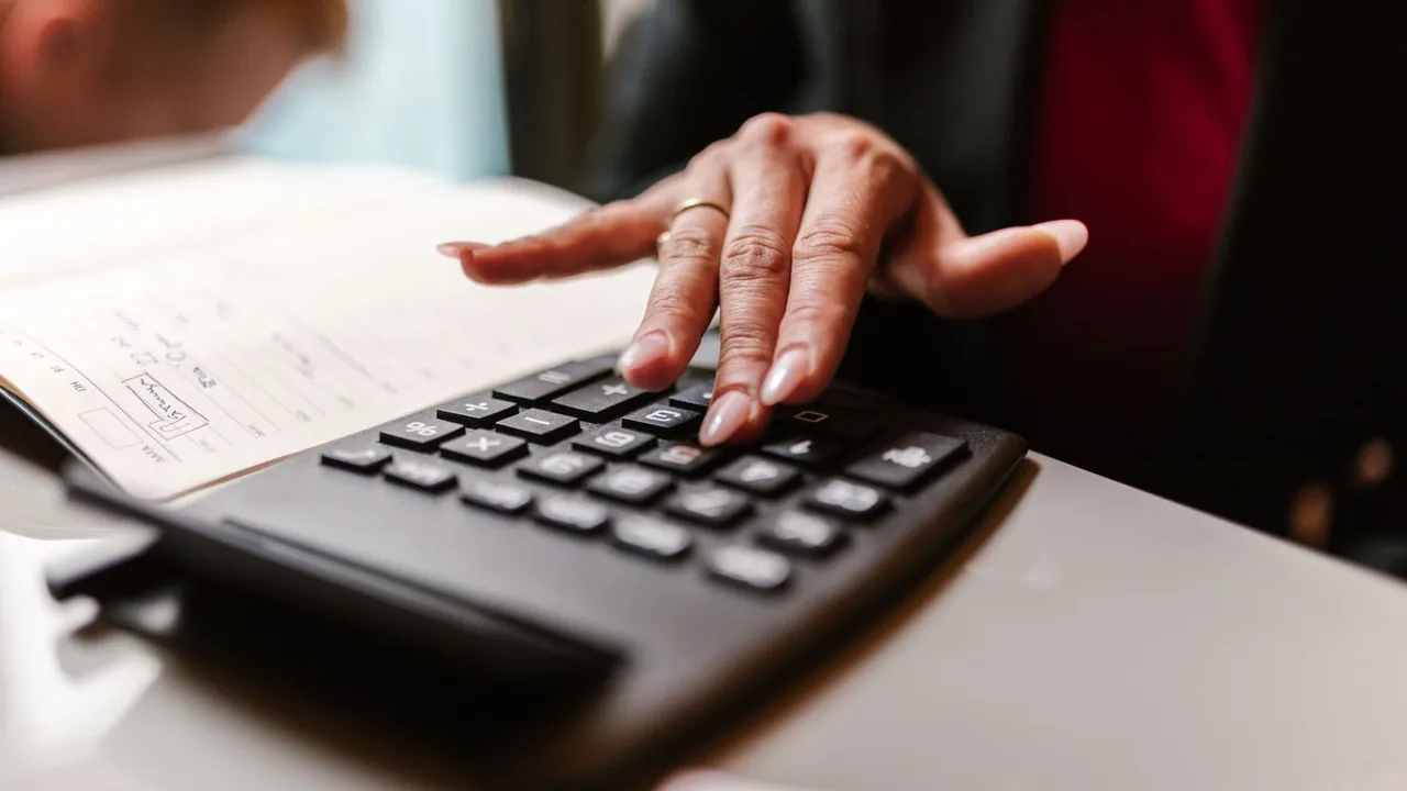 Main sur les touches d'une calculatrice noire, cahier de notes manuscrites à côté