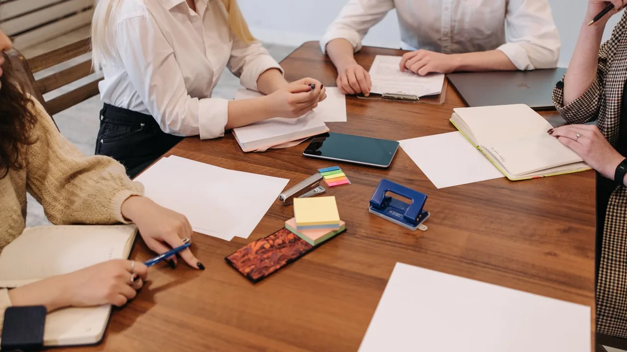 Équipe réunie autour d'une table en bois avec papiers, carnets, notes adhésives et téléphone