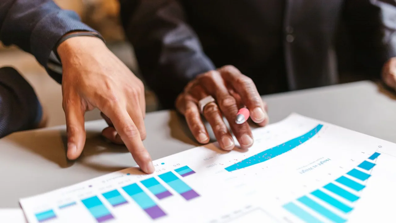 Mains qui pointent des graphiques en barres colorés imprimés sur une table