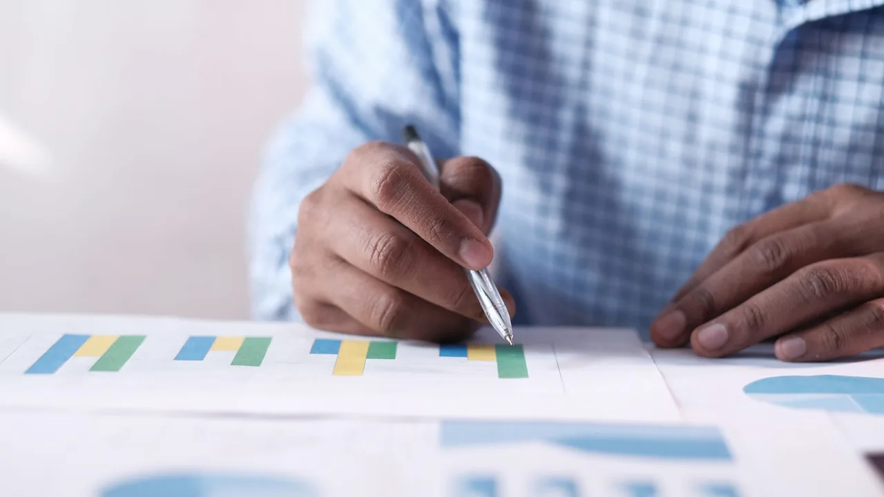 Un homme en chemise à carreaux annote des histogrammes colorés imprimés, stylo à la main