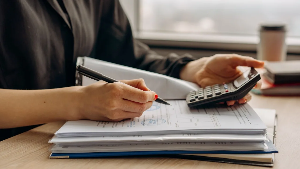 Gros plan d'une personne qui utilise une calculatrice parmi des documents financiers