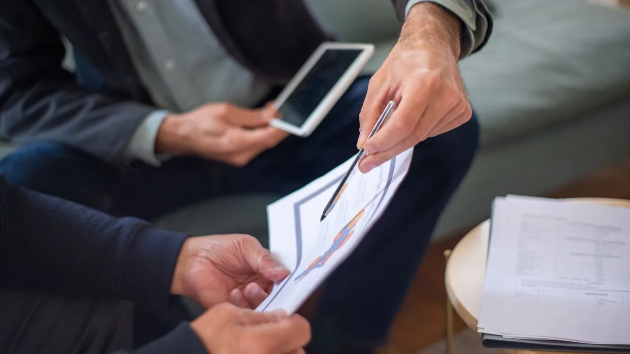 Deux personnes examinent un document et une tablette lors d'un rendez-vous