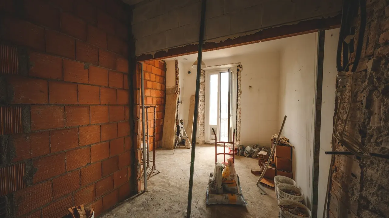 Une pièce en cours de rénovation aux murs de briques apparentes, avec des matériaux de chantier au sol