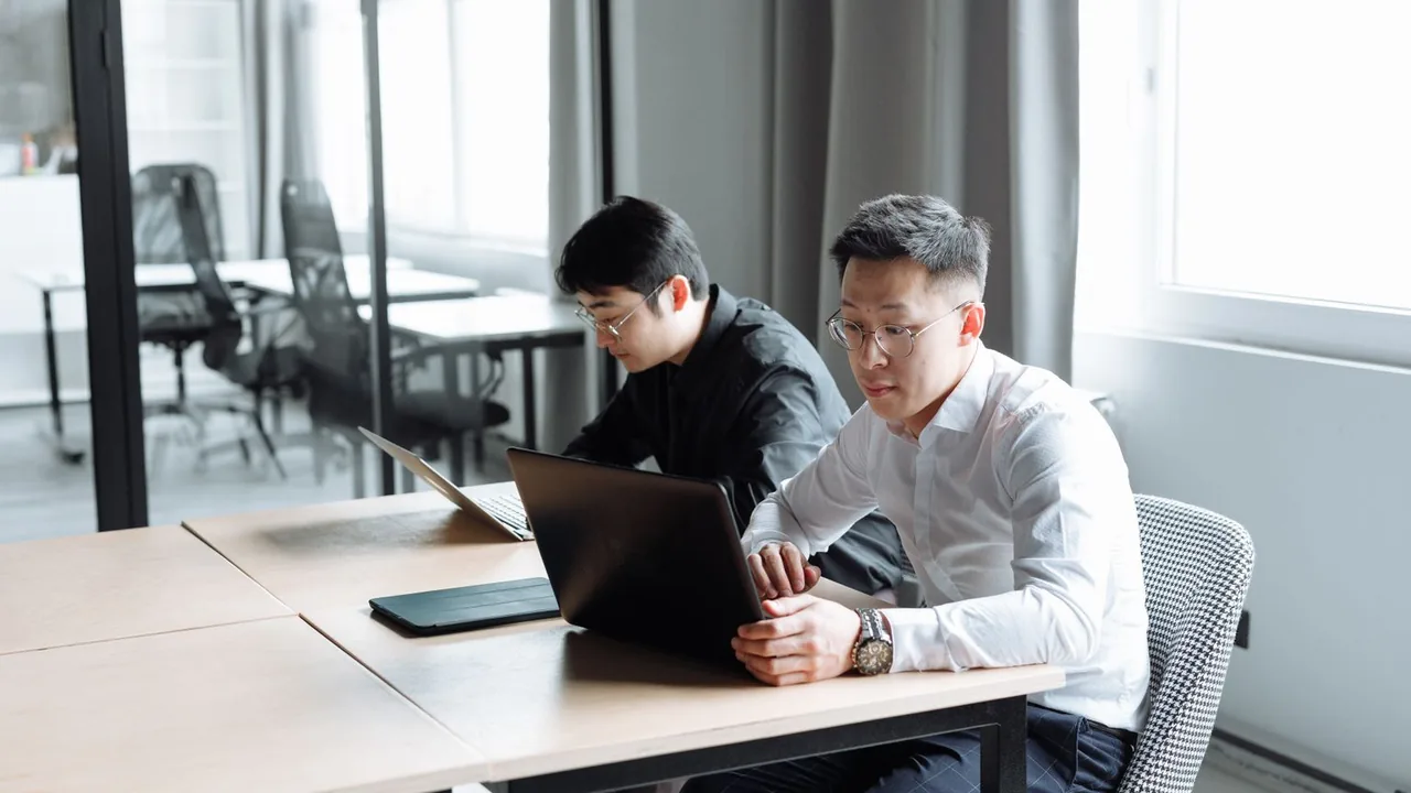 Deux collègues concentrés sur leurs ordinateurs portables dans un bureau lumineux