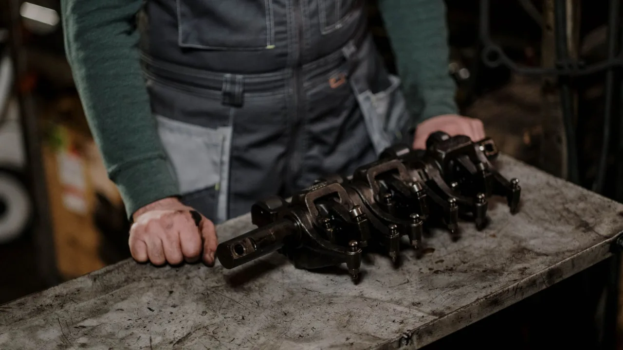 Mains d'un opérateur posées près d'une pièce mécanique métallique sur un établi d'atelier