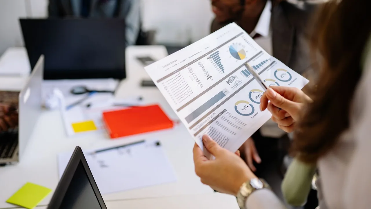 Mains tenant un rapport imprimé avec des graphiques lors d'une réunion d'équipe