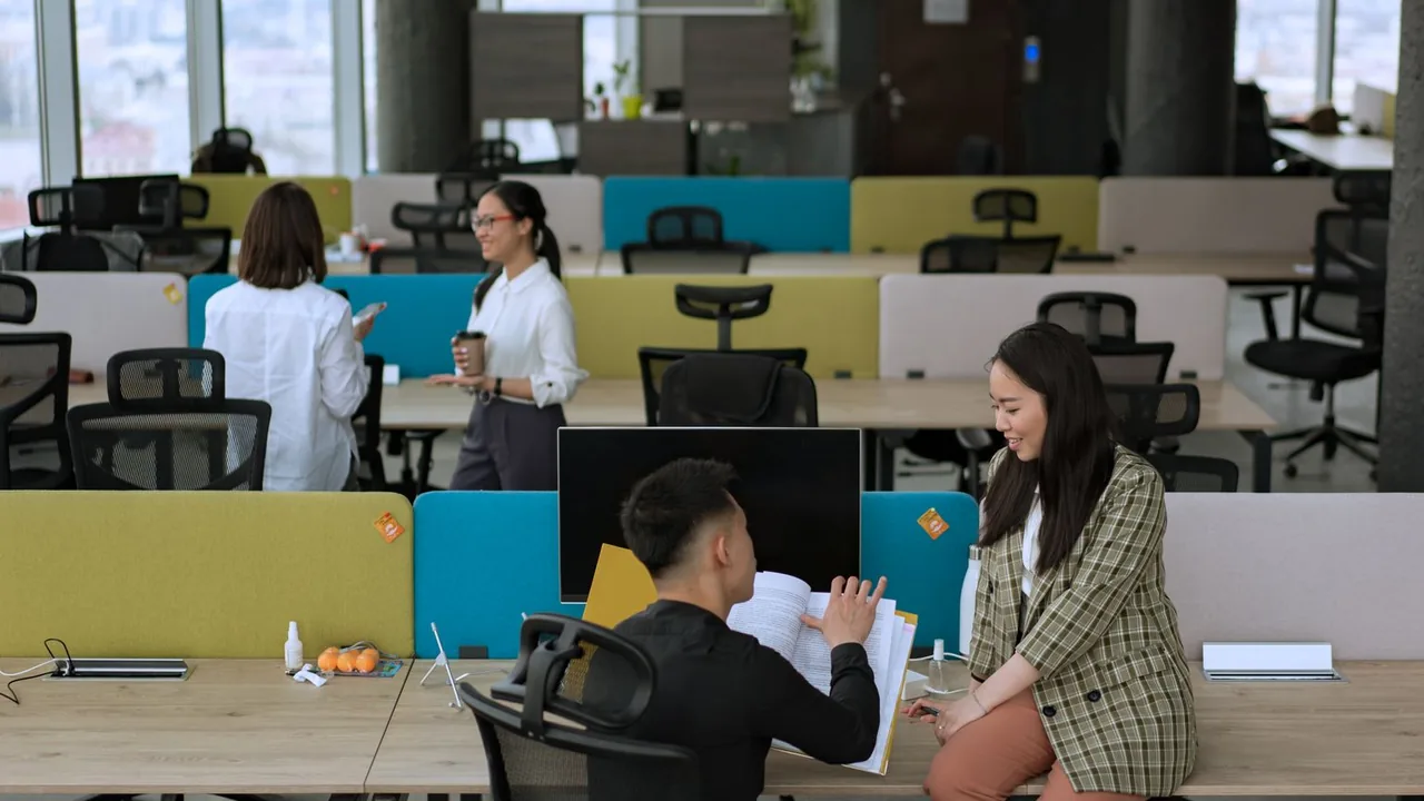 Grand espace de bureau ouvert où des collaborateurs travaillent et échangent à leurs postes