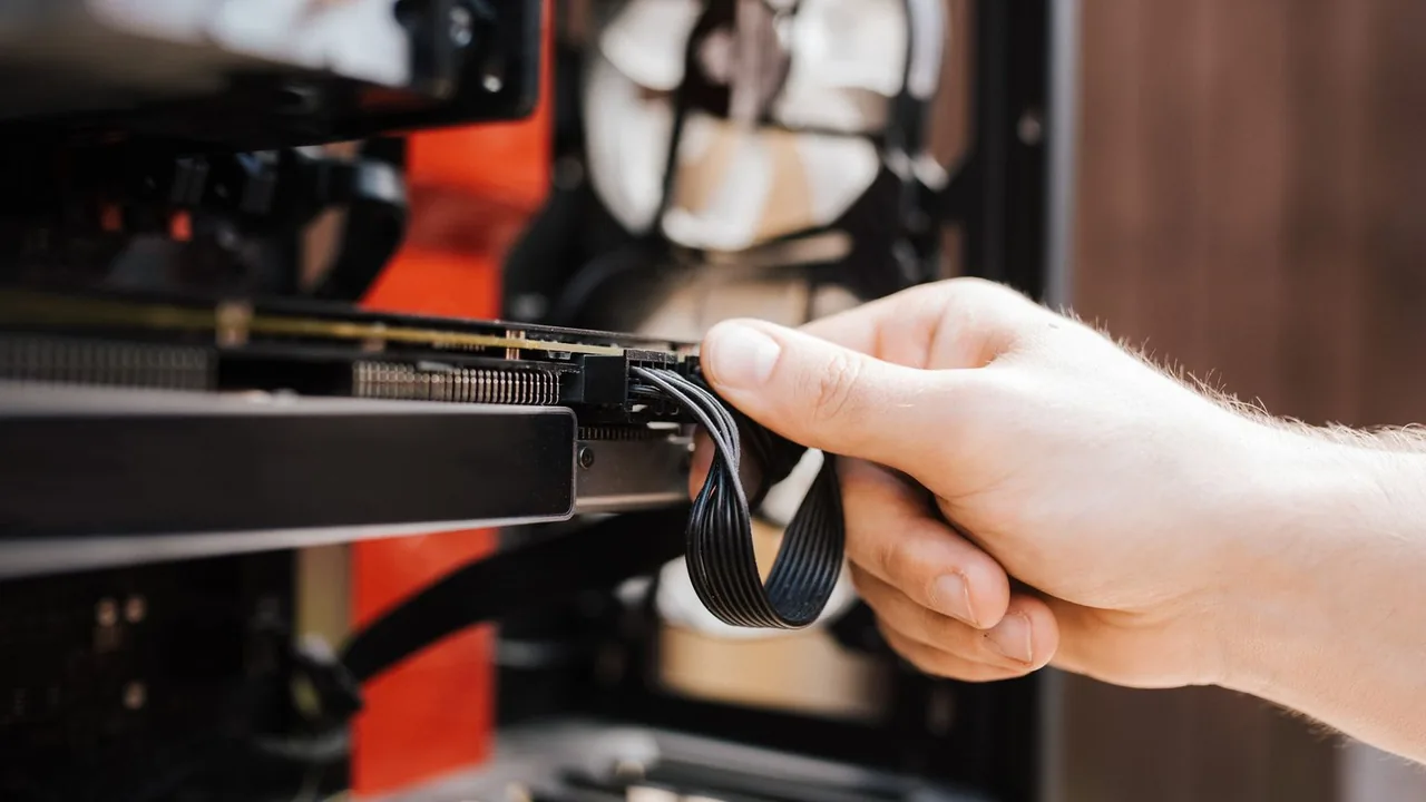 Une main connecte un câble à une carte graphique dans une tour d'ordinateur