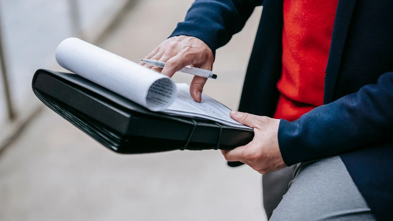 Les mains d'un professionnel feuillettent des documents glissés dans un porte-bloc