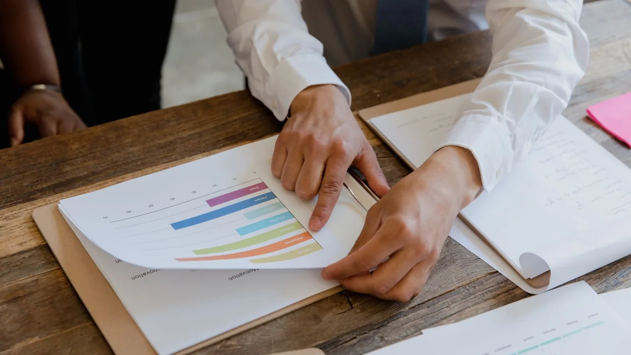 Mains pointant un graphique en barres colorées sur une feuille posée sur une table en bois