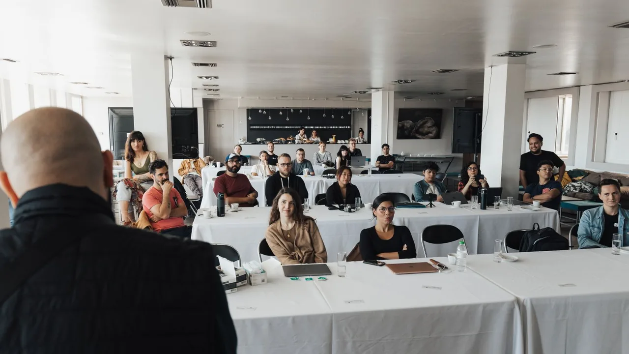 Des professionnels assistent à une présentation dans une salle de conférence, assis à des tables