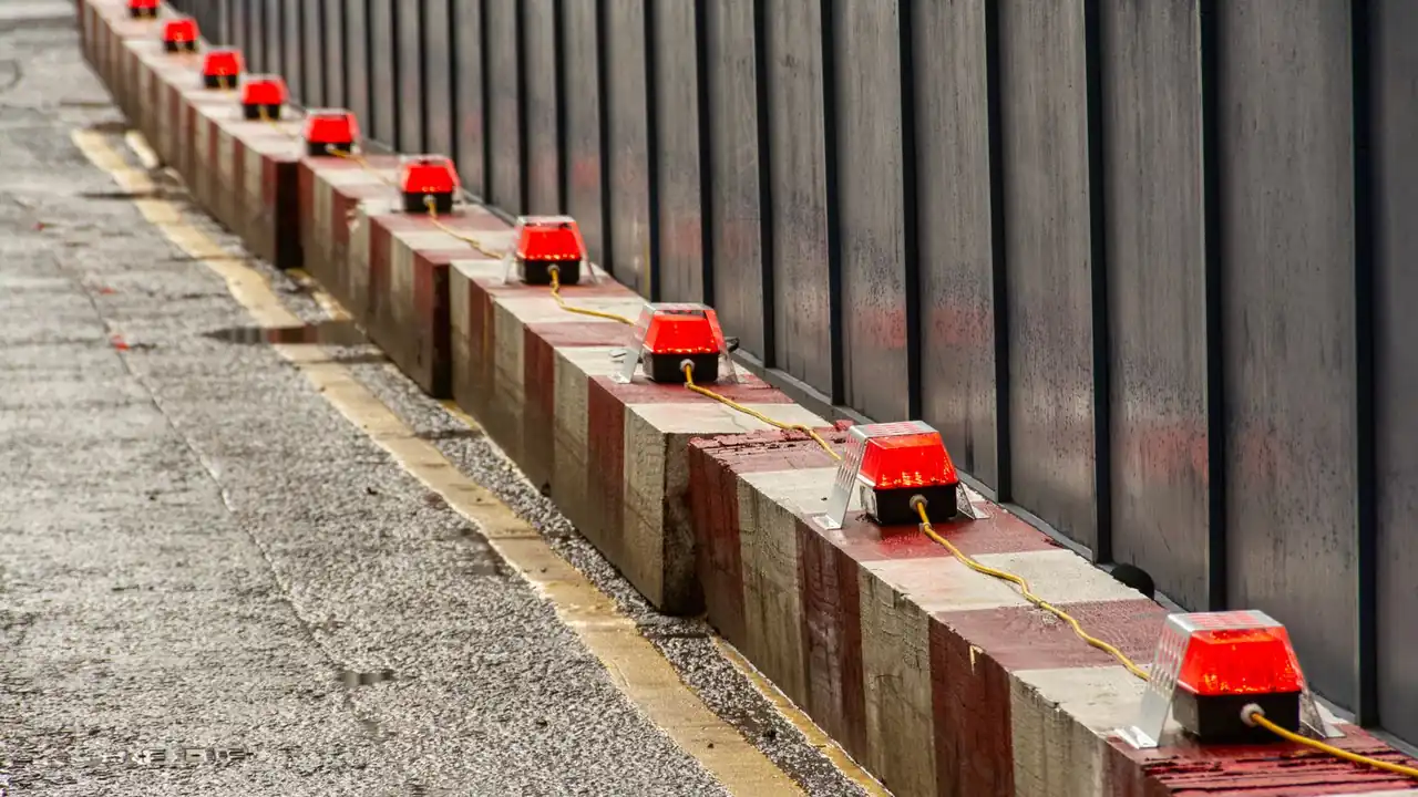 Rangée de feux d'avertissement rouges posés sur des blocs de chantier le long d'une palissade