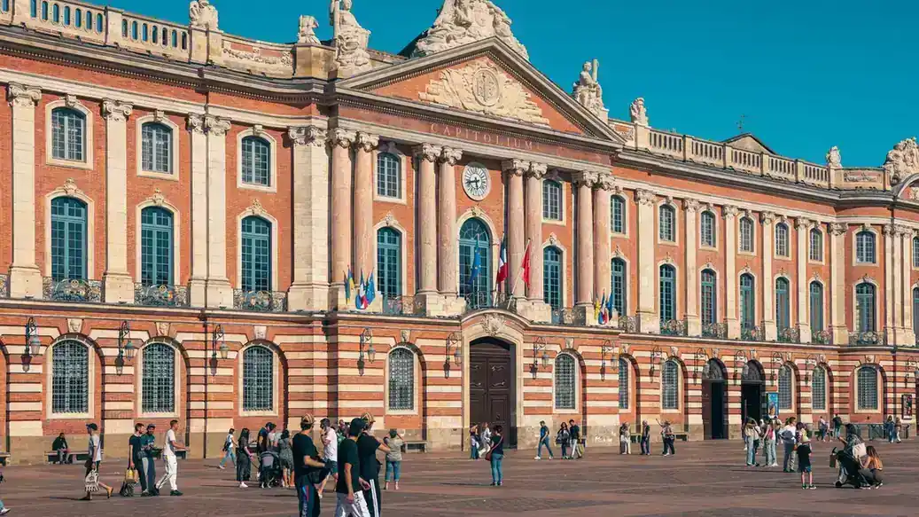 Façade en brique rose du Capitole de Toulouse, hôtel de ville, sur une place ensoleillée