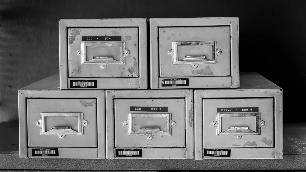 Cinq boîtes à fiches métalliques empilées, en noir et blanc