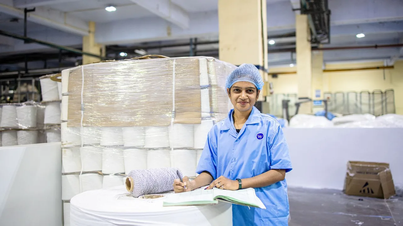 Une ouvrière note des informations sur des bobines de fil dans une usine textile