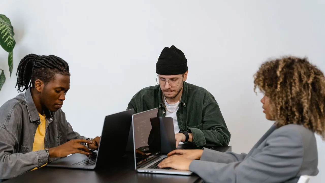 Trois jeunes collègues travaillent sur leurs ordinateurs portables autour d'une même table