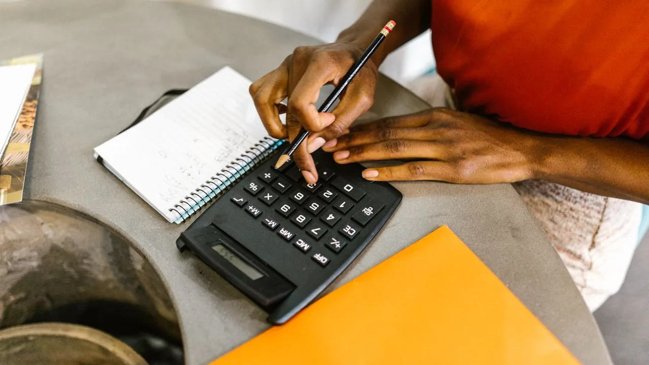 Femme qui calcule un budget avec une calculatrice et un bloc-notes