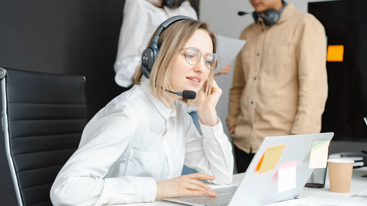 Une conseillère clientèle équipée d'un casque-micro travaille sur son ordinateur portable dans un bureau