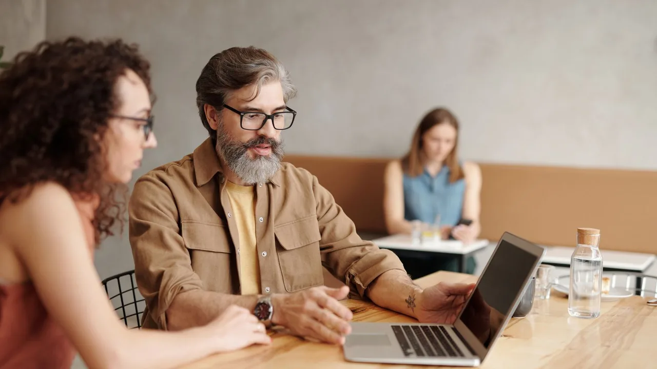 Deux collègues font le point sur un ordinateur portable dans un bureau, à l'heure de choisir entre plusieurs formules