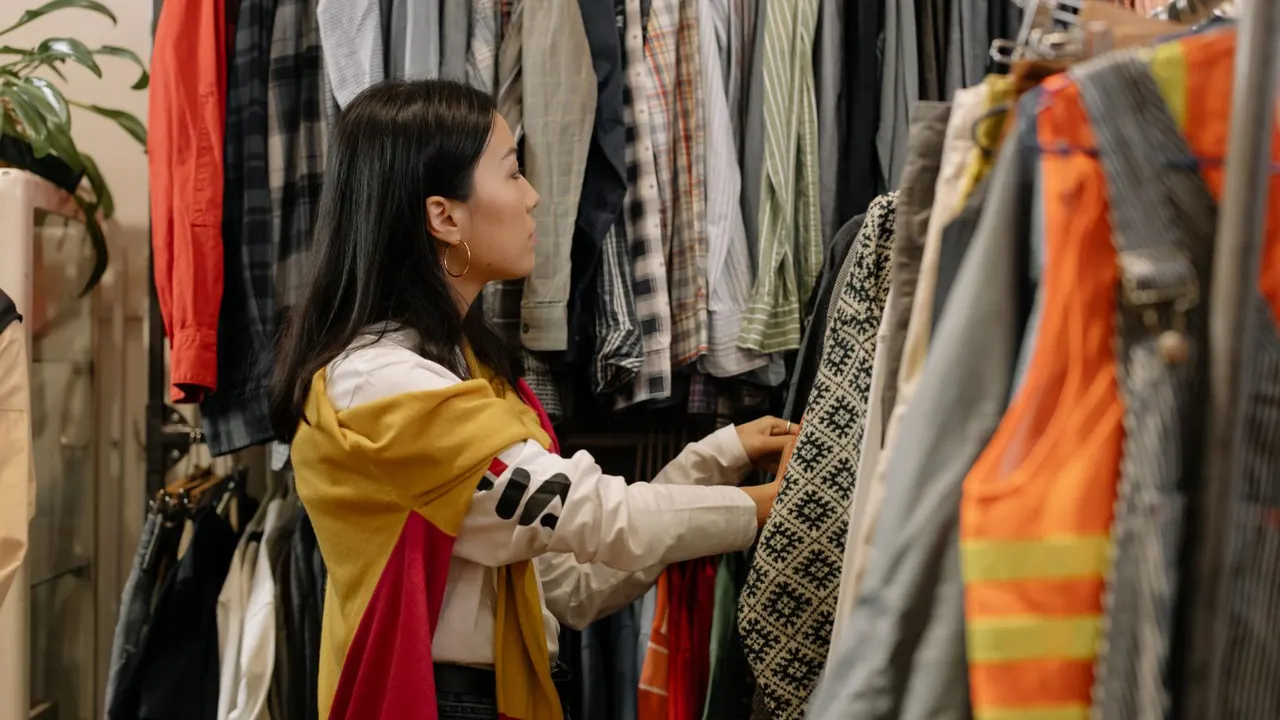 Une cliente parcourt les portants d'un magasin de vêtements aux tenues colorées