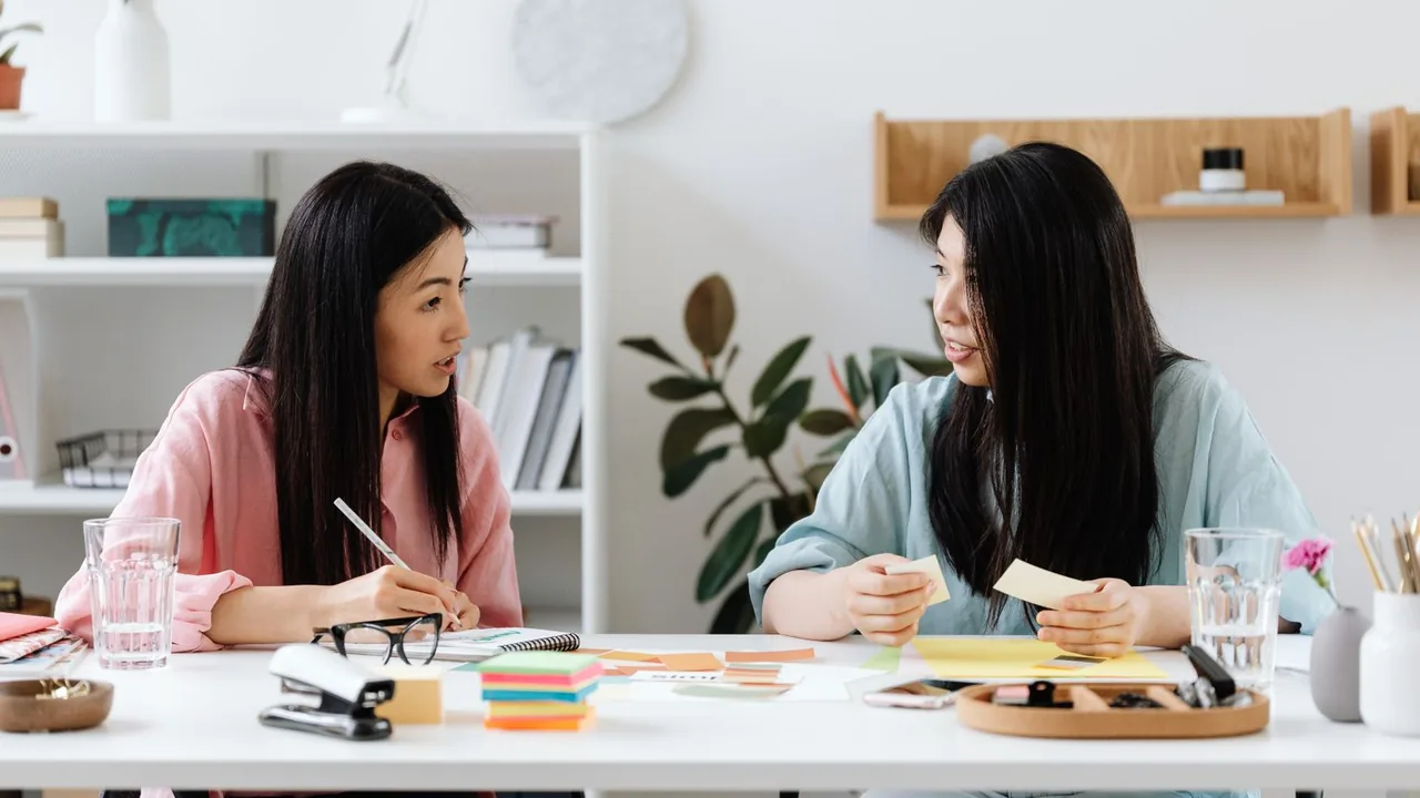 Deux femmes travaillent à un bureau avec des notes adhésives et de la papeterie