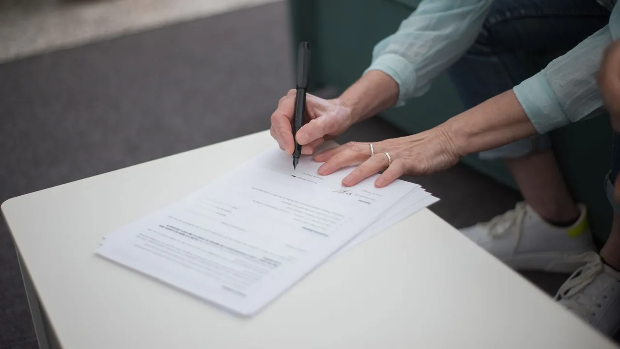 Mains signant des documents sur une table, vue rapprochée
