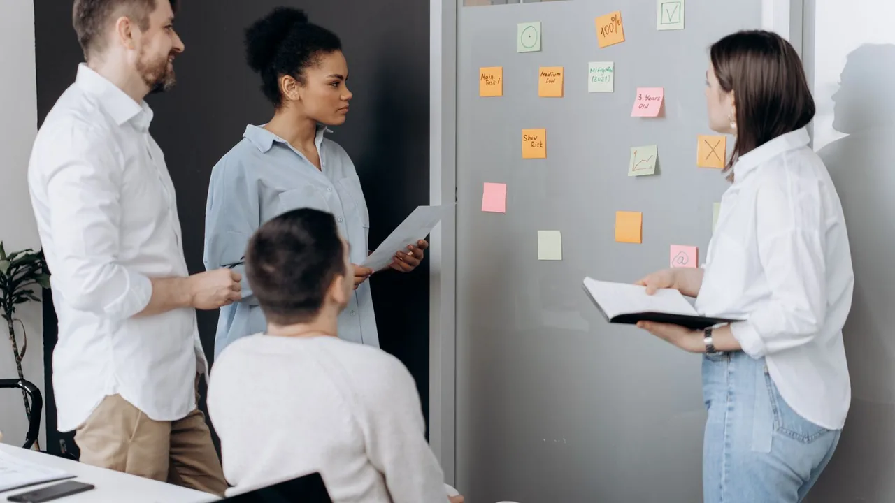 Une équipe réunie autour d'un mur de notes adhésives dans un bureau.