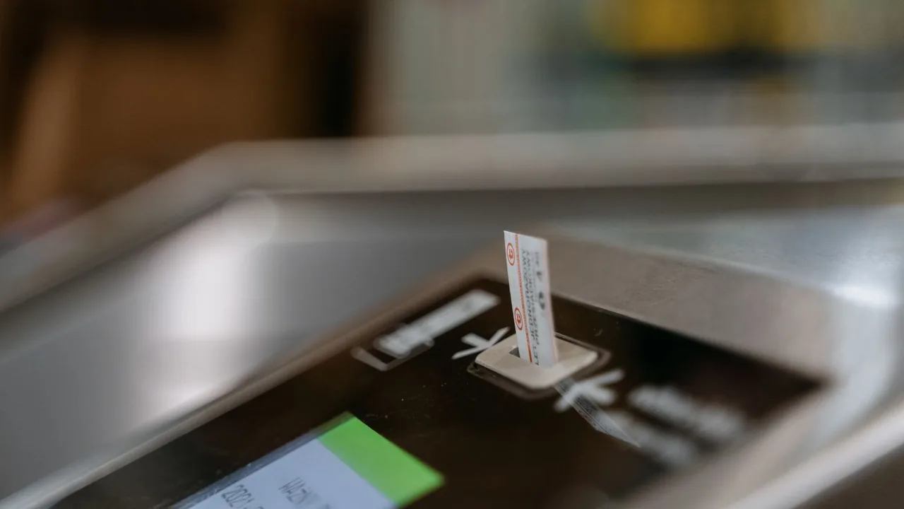 Gros plan d'un ticket de transport glissé dans la fente d'un portillon de validation