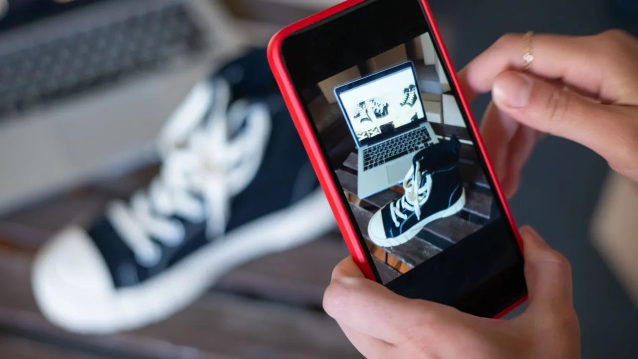 Mains photographiant une paire de baskets avec un smartphone pour une boutique en ligne