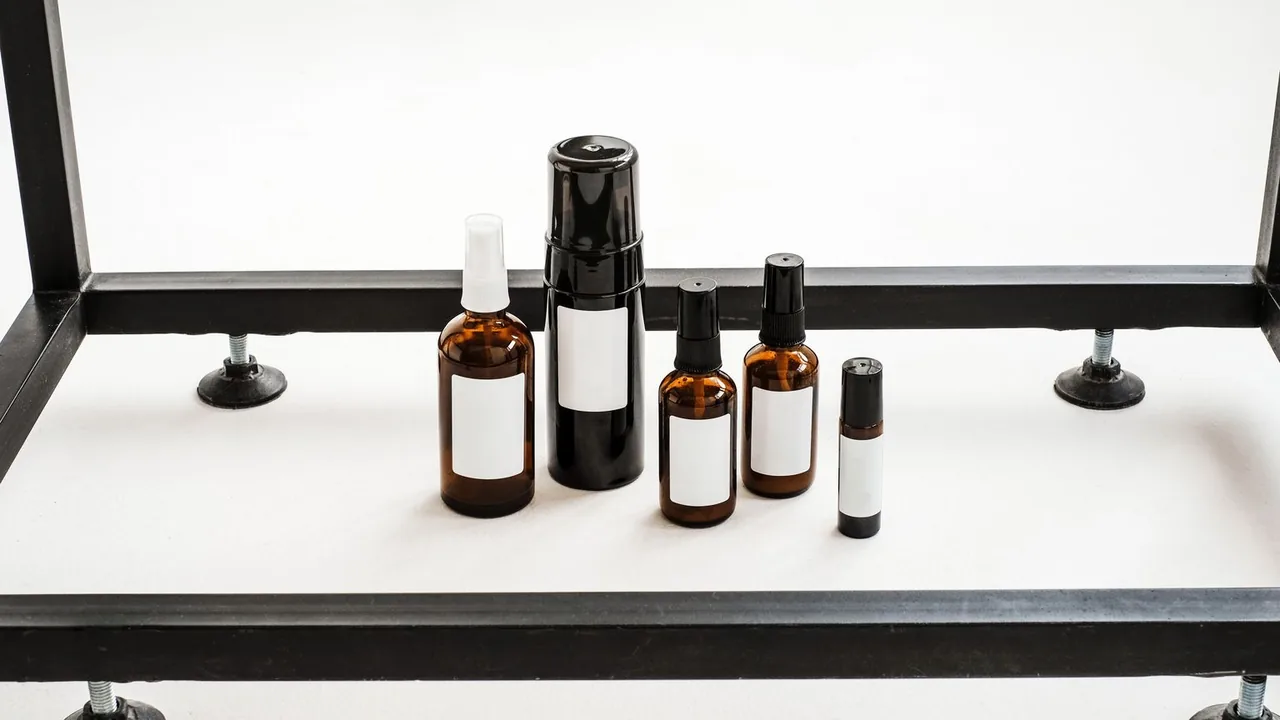 Flacons de cosmétique ambrés et noirs, aux étiquettes blanches vierges, posés sur un plateau blanc.