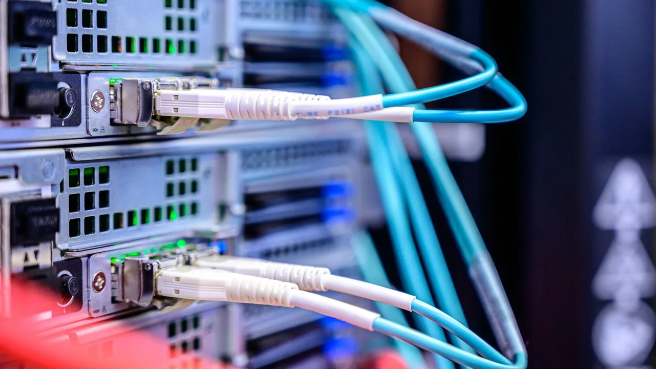 Gros plan sur des câbles de fibre optique turquoise branchés sur des équipements d'une baie