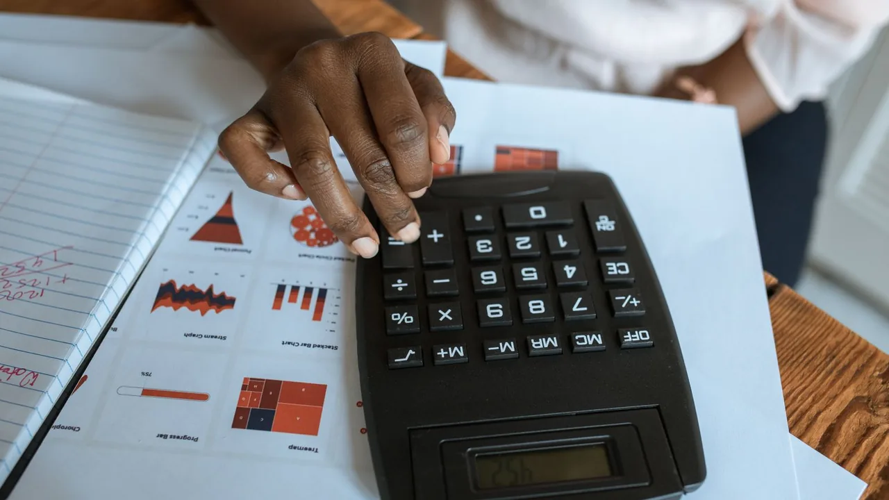 Une personne utilise une calculatrice sur un bureau couvert de graphiques imprimés.