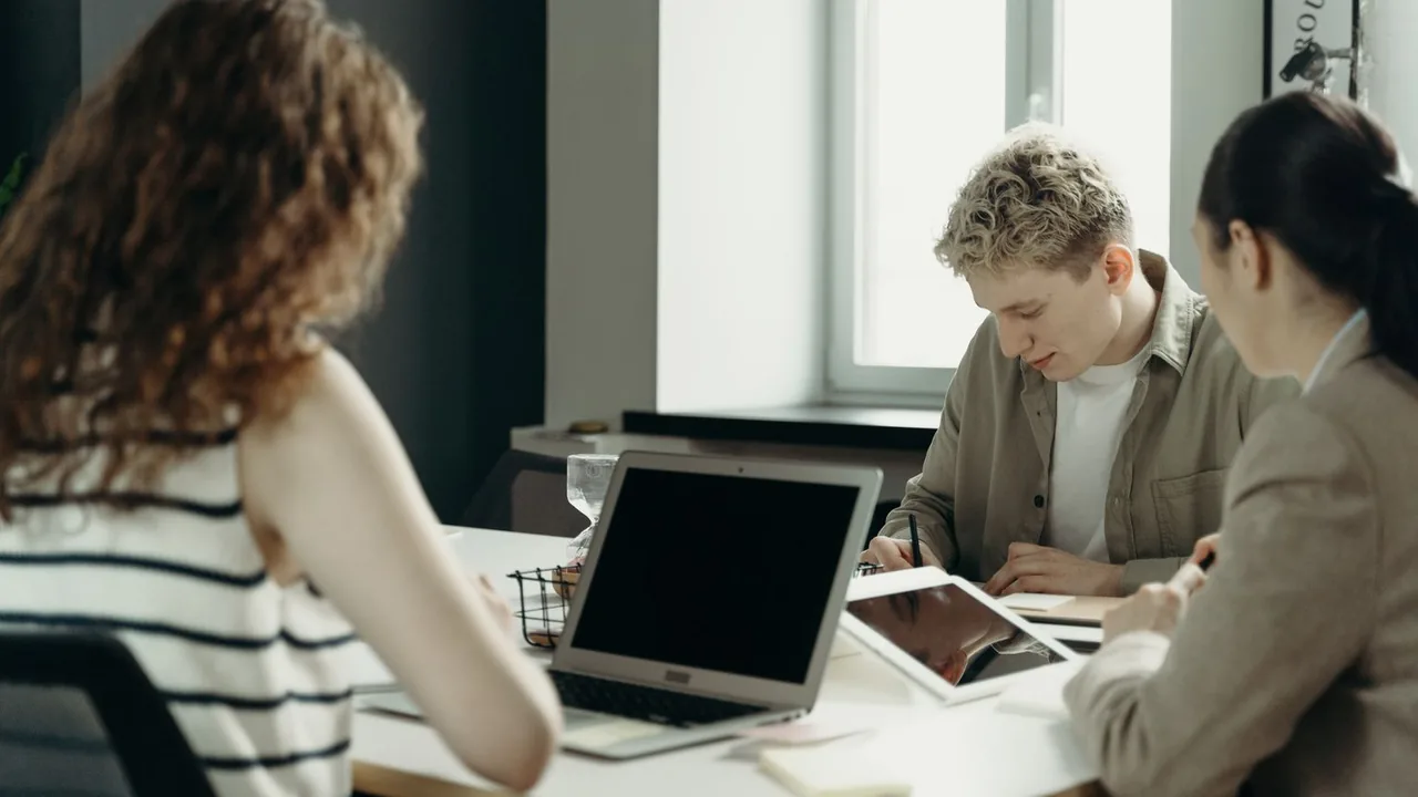 Des collègues réunis autour d'une table de bureau, devant un ordinateur portable et une tablette.