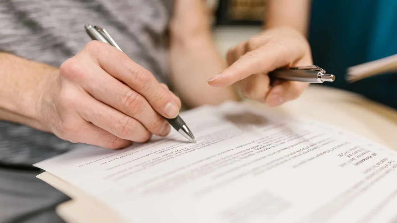 Deux personnes relisent un contrat et signent au stylo