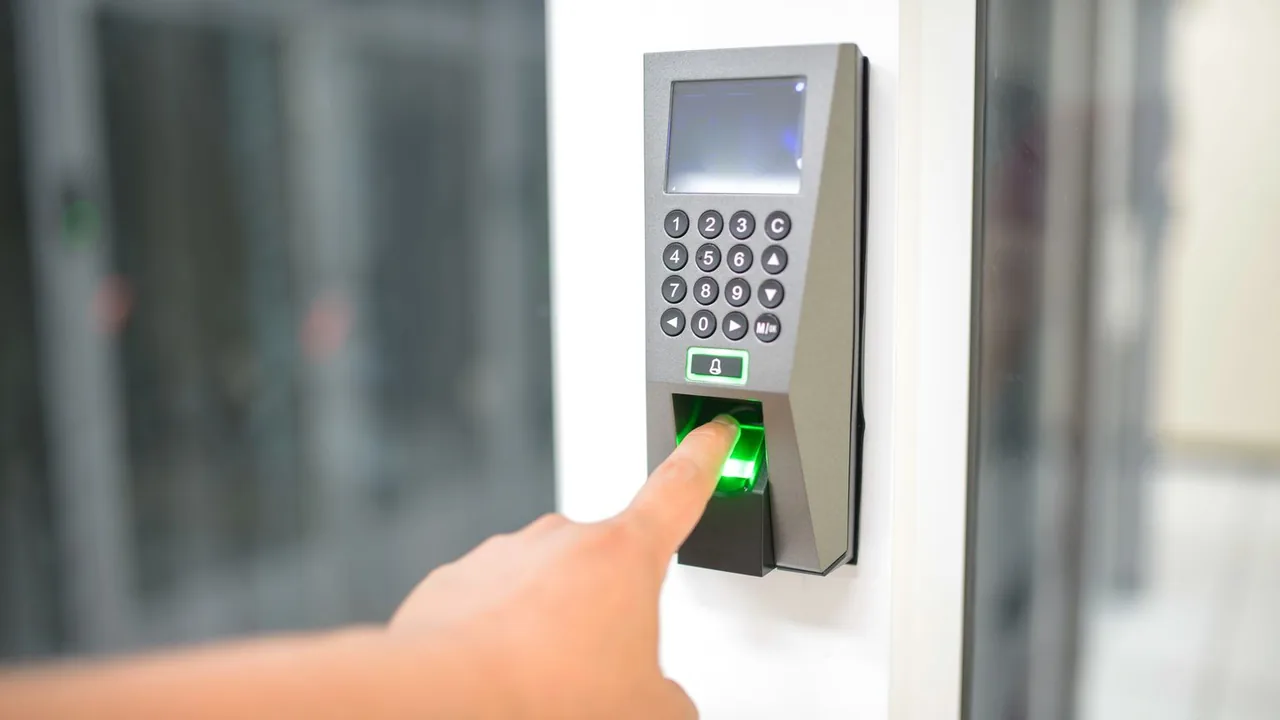 Un doigt posé sur un lecteur d'empreintes à clavier numérique pour ouvrir une porte