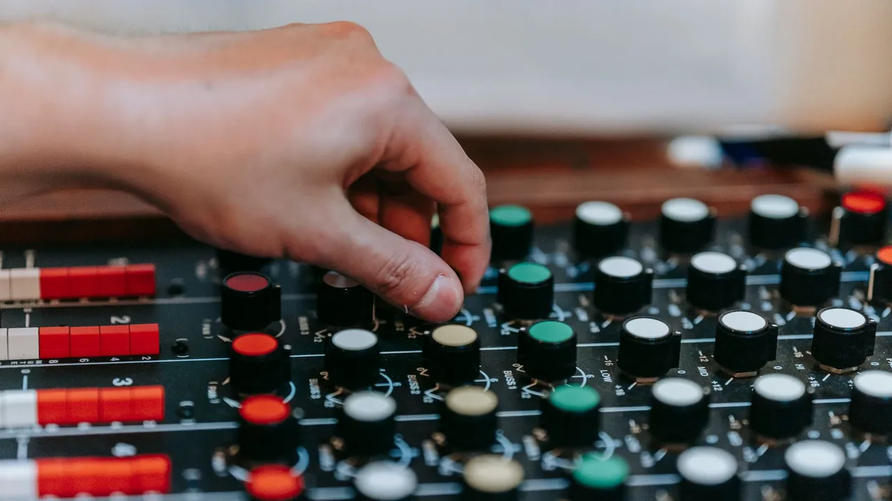 Gros plan d'une main qui règle les boutons d'une table de mixage audio