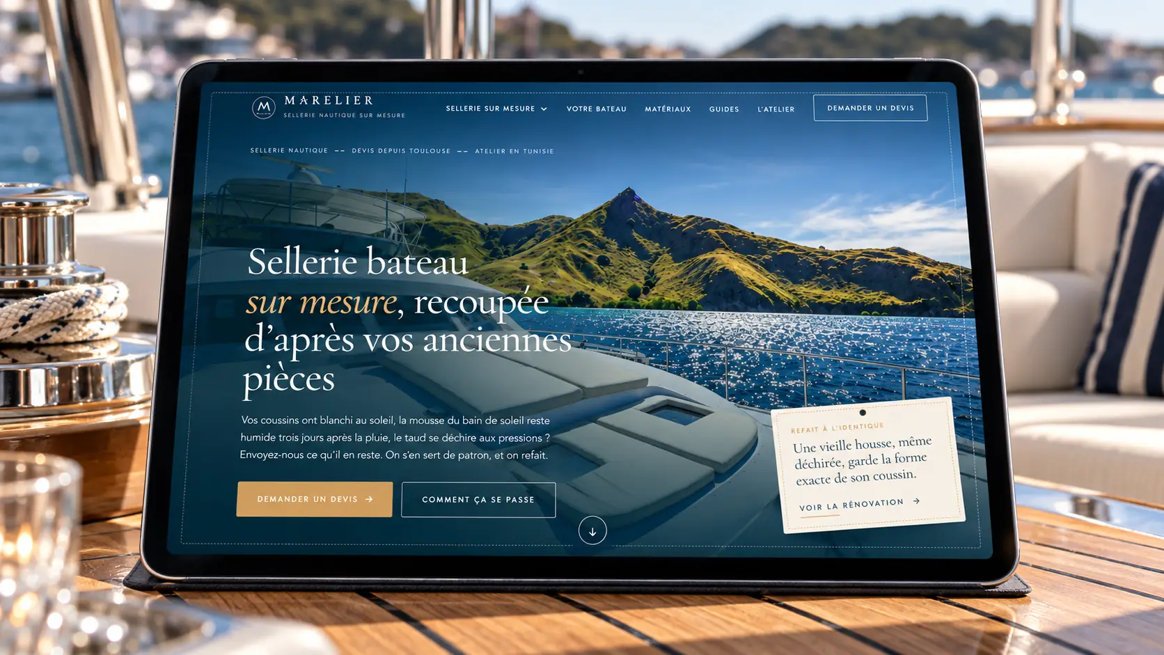 Le site Marelier sur une tablette posée sur la table en teck d'un cockpit de yacht
