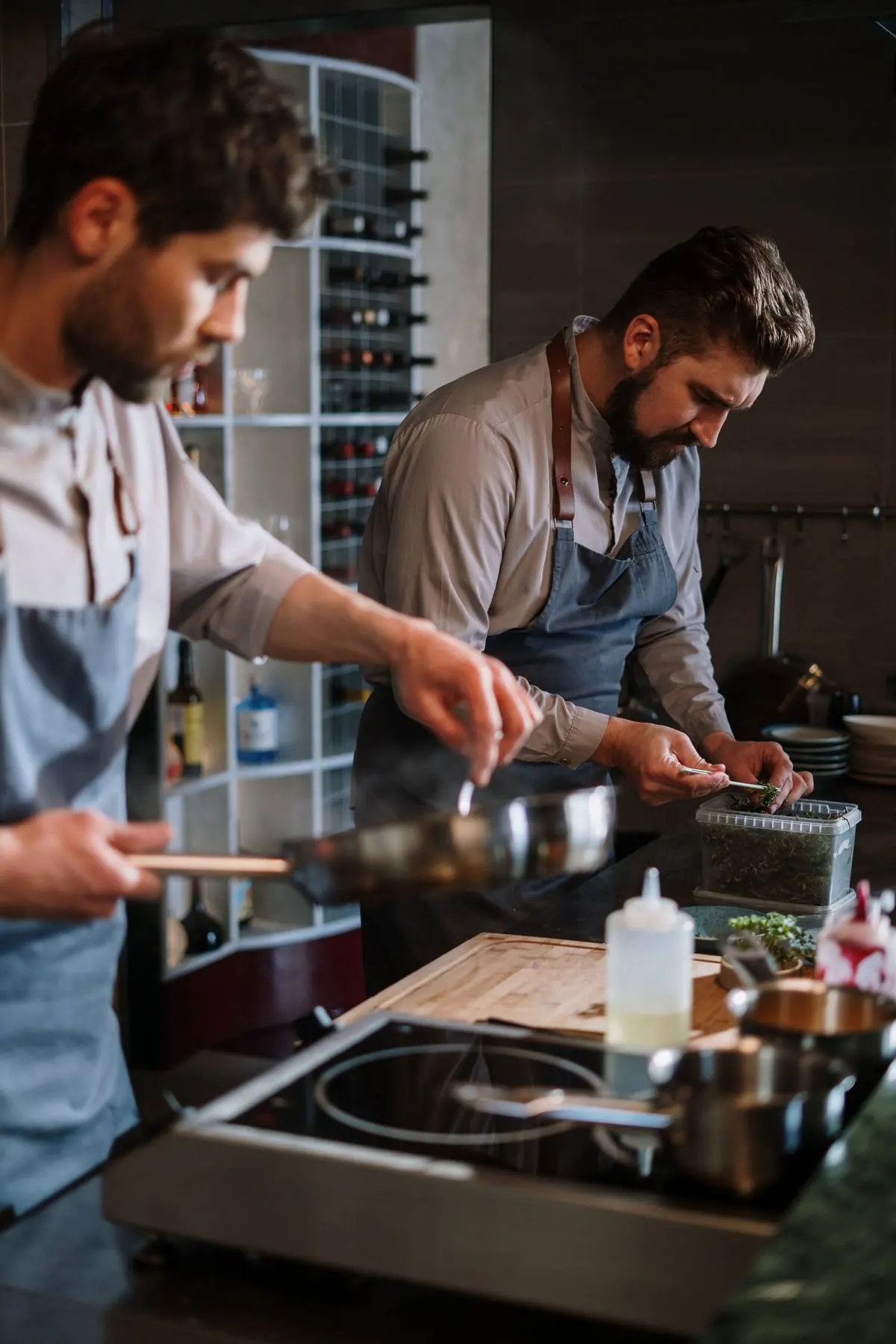 Deux chefs en cuisine professionnelle ouverte préparant des plats