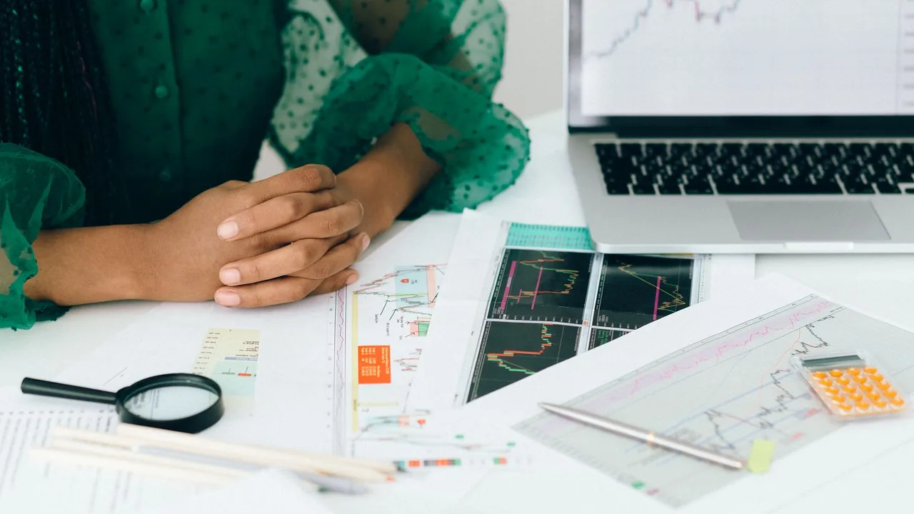 Graphiques imprimés, loupe et calculatrice étalés devant une personne assise au bureau