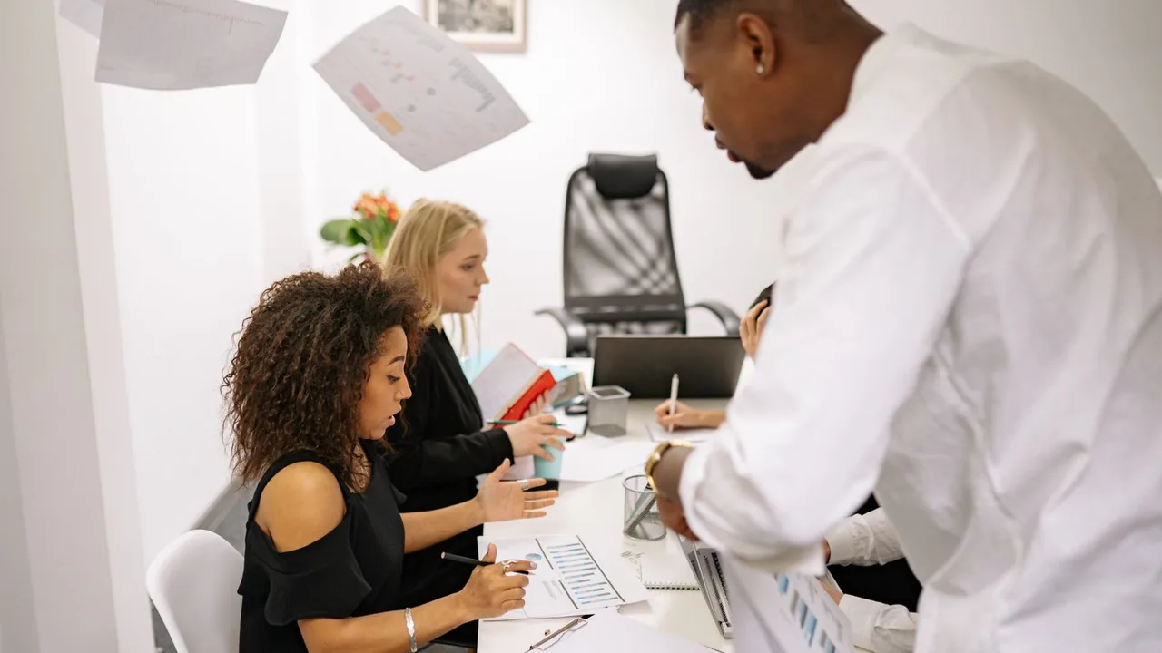 Une équipe commerciale penchée sur des documents autour d'une table de réunion dans un bureau lumineux