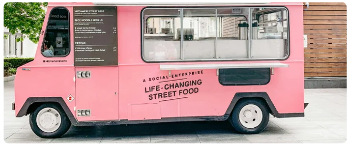 Un camion de nourriture rose garé sur le bord d'une rue